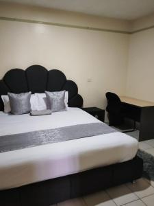 ein großes Bett mit einem großen Kopfteil in einem Zimmer in der Unterkunft Peridot Suites in Nairobi