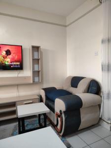 ein Wohnzimmer mit einem Sofa und einem TV in der Unterkunft Peridot Suites in Nairobi