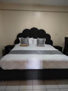 ein großes Bett mit einem großen schwarzen Kopfteil in einem Zimmer in der Unterkunft Peridot Suites in Nairobi