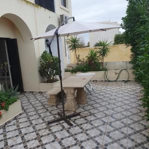 a bench with an umbrella on a patio at Maison de vacances à la mer 5mn à pieds in Borj el Khessous