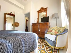 een slaapkamer met een bed, een stoel en een dressoir bij At Fourth in Cagliari