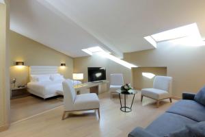 1 dormitorio con cama, sofá y TV en NH Collection Cáceres Palacio de Oquendo en Cáceres