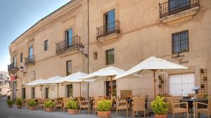 a group of tables and umbrellas in front of a building at NH Collection Cáceres Palacio de Oquendo in Cáceres