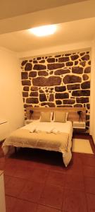 a bedroom with a bed in front of a stone wall at Recanto da Neta in Seia