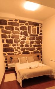 1 dormitorio con 1 cama y pared de piedra en Recanto da Neta, en Seia