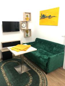 een woonkamer met een groene bank en een tafel bij J & A in Tirana