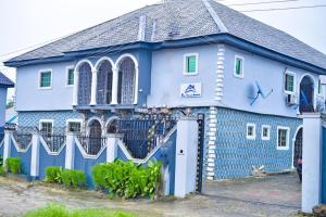a blue house with a fence in front of it at Mena's Home & Apartment in Ughelli