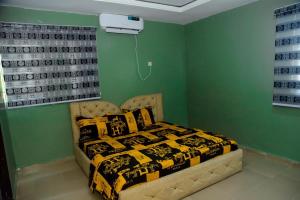 Mena's Home & Apartment في Ughelli: غرفة نوم بسرير في غرفة بجدران خضراء