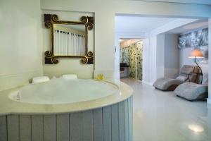 a large bathroom with a tub and a living room at Pousada Bora Bora in Bombinhas