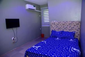 a bedroom with a bed with a blue comforter at Mena's Home & Apartment in Ughelli