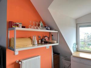 バラトンフレドにあるBalatonfüred Apartmentのキッチン(オレンジ色の壁、棚、ラジエーター付)