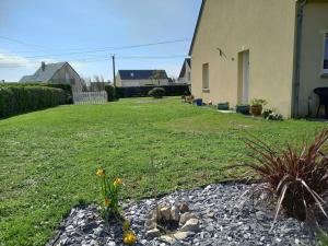 un patio con una casa y algunas flores en el césped en Maison 100m de la plage les pieds dans l'eau, en Surtainville