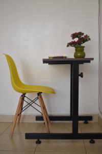 Juliett Wonder Furnished Apartment في نيروبي: كرسي اصفر جالس بجانب مكتب فيه نبات
