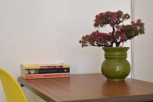 a green vase with flowers on a table with books at Juliett Wonder Furnished Apartment in Nairobi