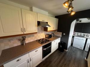 een keuken met witte kasten en een fornuis met oven bij Modern 3 Bedroom House Close to Liverpool Centre in West Derby