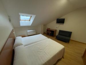 a bedroom with a large white bed and a chair at Hotel Alda Fogar do Mariñeiro in Ribadeo