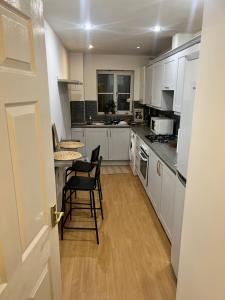 a kitchen with white cabinets and a table and chairs at Serenity in Seven Kings