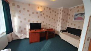 a room with a desk with a tv and a couch at Hotel Zbyszko in Szczecin