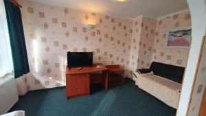 Zimmer mit einem Schreibtisch, einem TV und einem Sofa in der Unterkunft Hotel Zbyszko in Stettin