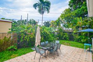 um pátio com uma mesa com um guarda-sol e cadeiras em Discover Serenity in this Tranquil Miami Home em Miami
