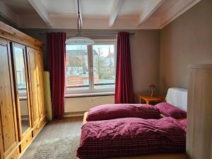 - une chambre avec un lit et une fenêtre avec des rideaux rouges dans l'établissement Ferienwohnung im Dachgeschoss mit Aufzug, à Rostock