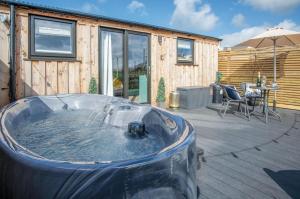 una bañera de hidromasaje en un patio con mesa y sillas en Willows Rest - 1 Bed Shepherds Hut - Pentlepoir en Saundersfoot