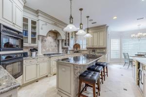 a kitchen with white cabinets and a large island with bar stools at Casa Isla Paraiso in Destin