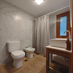 a white bathroom with a toilet and a sink at ANFITEATRO APARTS & LOFTS in San Carlos de Bariloche