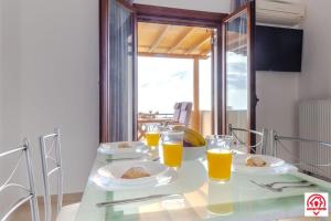 una mesa con dos platos de comida y vasos de zumo de naranja en Villa naya, en Megalokori