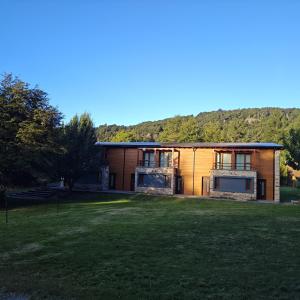 a house with a large grass field in front of it at ANFITEATRO APARTS & LOFTS in San Carlos de Bariloche