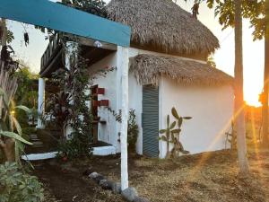 une petite maison blanche avec un toit de paille dans l'établissement Blah Blah House, à El Paredón Buena Vista