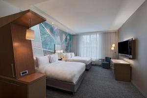 um quarto de hotel com duas camas e uma televisão de ecrã plano em Courtyard by Marriott Jackson Madison em Madison