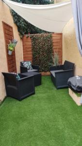 un patio con 3 sillas y césped verde en studio 1 étoile paisible,4 couchages,jardin privé en Les Adrets de l'Esterel