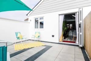 a white house with a patio with chairs and an open door at Little Bright House in Whitstable