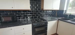 uma cozinha com um fogão e uma parede de azulejos pretos em Beresford House em Longford