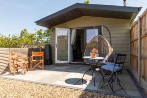 a patio with a table and chairs on a house at Pear Tree Cabin in Whitstable