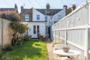 a small backyard with a white fence and a table at Painter Cottage in Whitstable