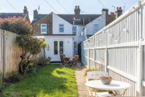 małe podwórko z białym płotem i stołem w obiekcie Painter Cottage w mieście Whitstable