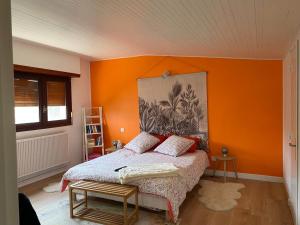 a bedroom with a bed with an orange wall at Chambre Sayulita/Spa/piscine in Idron