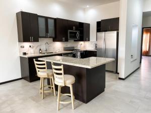 una cocina con armarios negros y una barra con taburetes en New Built Condo minutes to Beach! en Puerto Peñasco