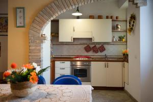 - une cuisine avec des placards blancs et une table fleurie dans l'établissement l'Apostolo e il Navarca, à Ortona