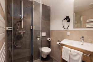 a bathroom with a shower and a toilet and a sink at Hotel Restaurant Sennerbad in Ravensburg