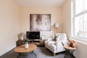 a living room with a white couch and a tv at Stylish 2 Bed with Free Private Parking! in Cheltenham