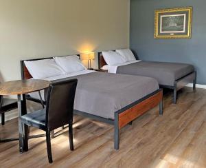 two beds in a room with a table and a chair at Red Carpet Inn - Houma in Houma