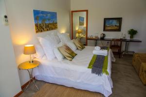 ein Schlafzimmer mit einem großen Bett mit weißer Bettwäsche und Kissen in der Unterkunft Upington African Vineyard Boutique Hotel & SPA in Kanoneiland