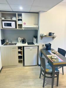 une petite cuisine avec une table et un évier dans l'établissement [Rêve doré] Studio Équipé, Wifi, Unique, à Lourdes