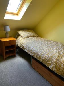 a bedroom with a bed and a nightstand with a window at Springwell Cottage in Fort William
