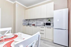 a white kitchen with a table and a white refrigerator at Grand Turan Business One-Room Apartments in Astana