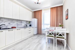 a kitchen with white cabinets and a white table at Grand Turan Business One-Room Apartments in Astana