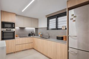 una cucina con armadietti in legno ed elettrodomestici in acciaio inossidabile di Athenian Riviera Secluded Apartment ad Atene